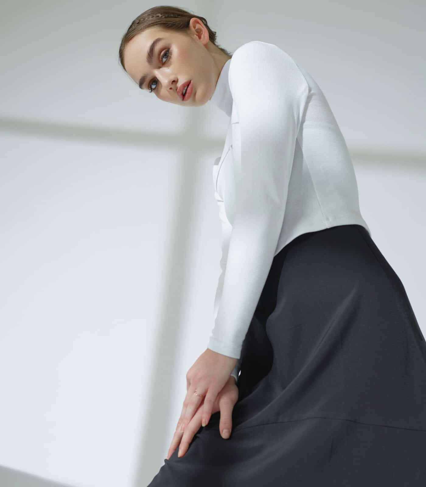Elegant woman in white blouse and black skirt posing indoors.