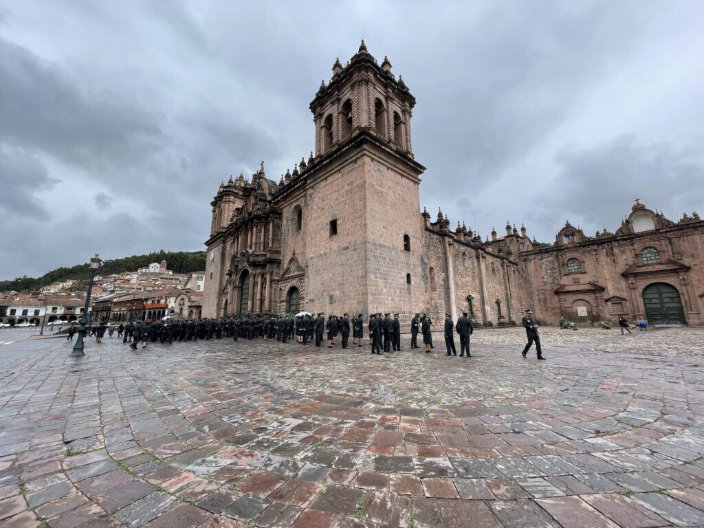 Historic cathedral in Mexico City with police officers on cobblestone plaza under cloudy sky.