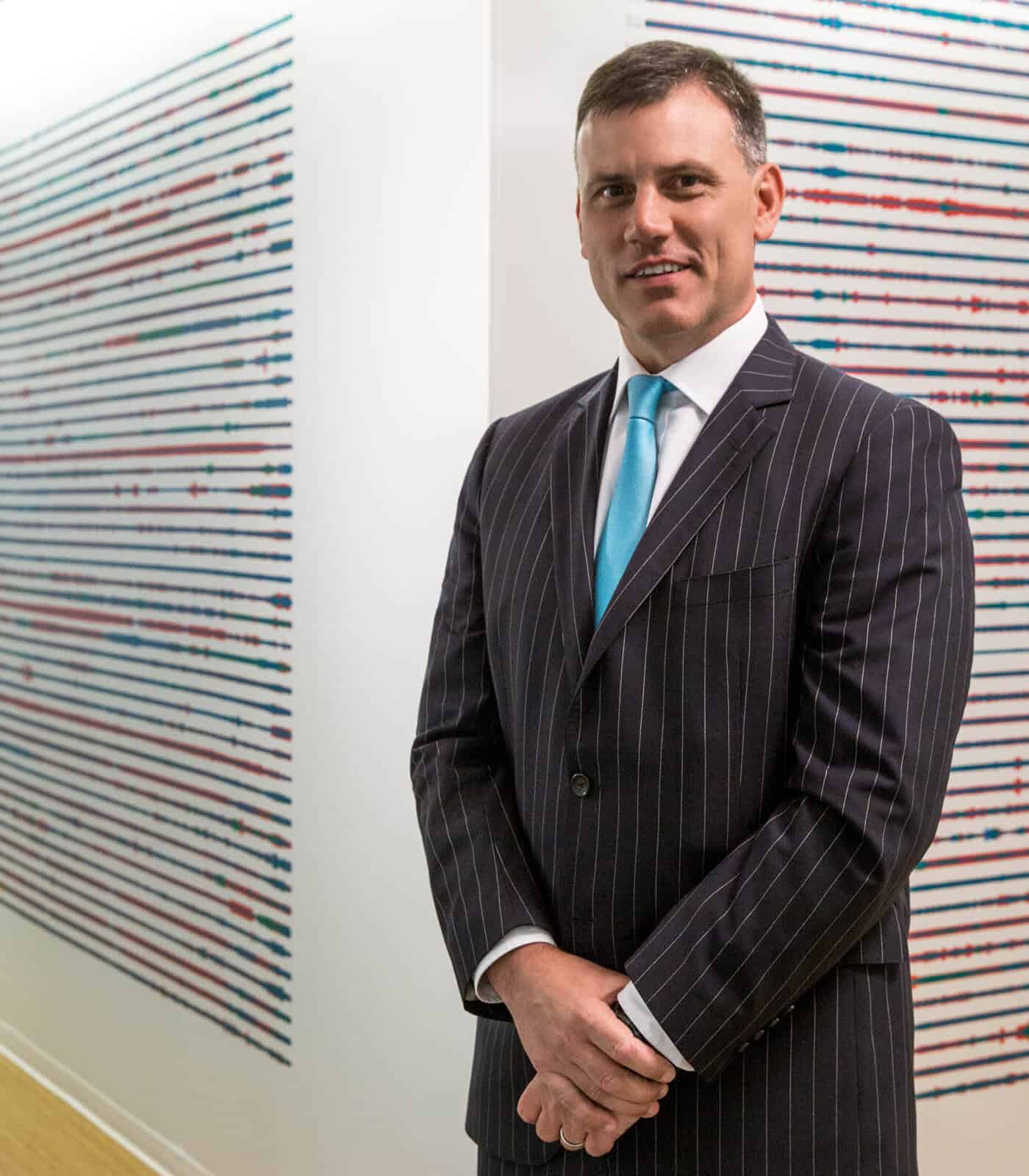 Businessman standing in front of colorful abstract art at NYC gallery.