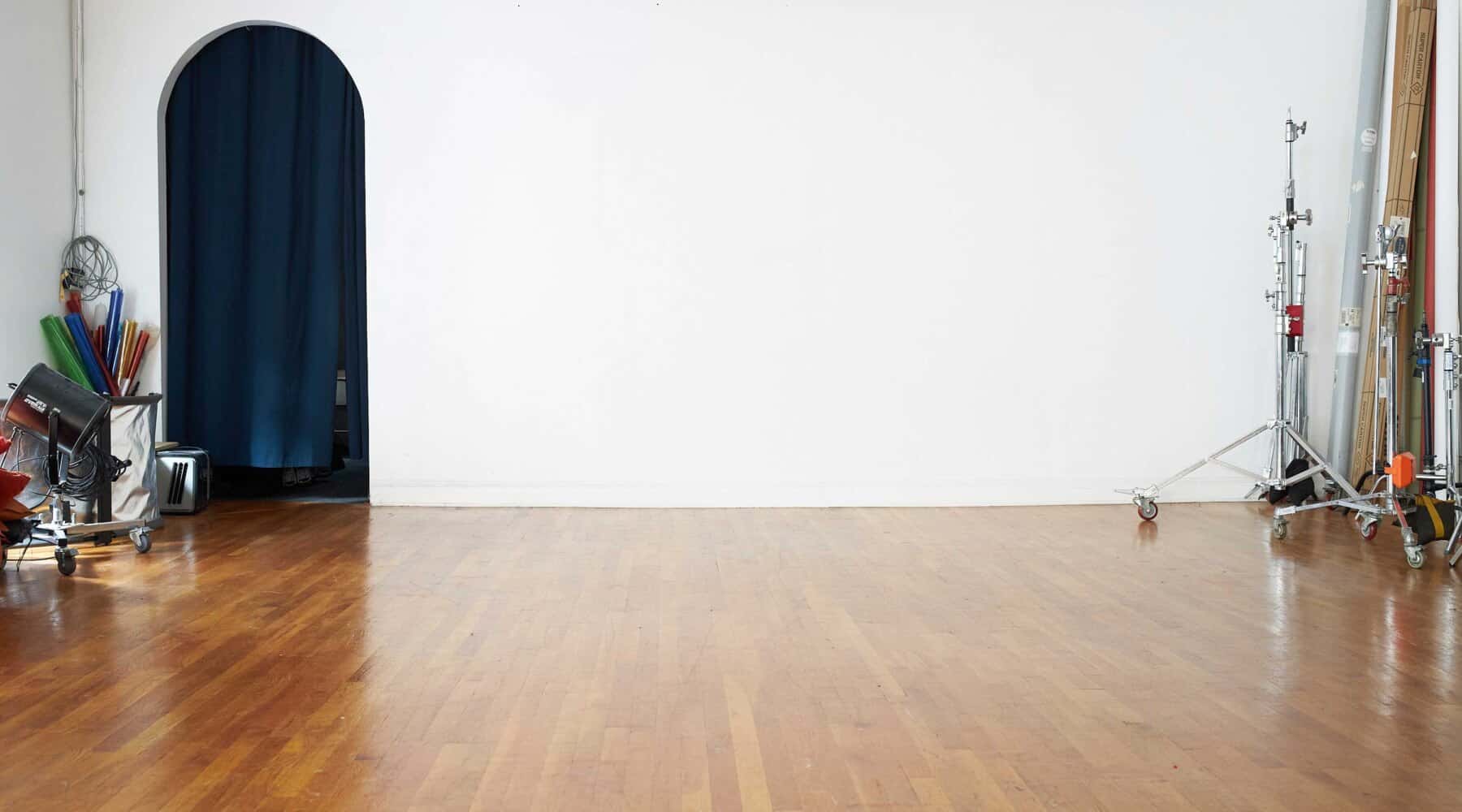 Studio photography space with wooden floor and minimal equipment setup.
