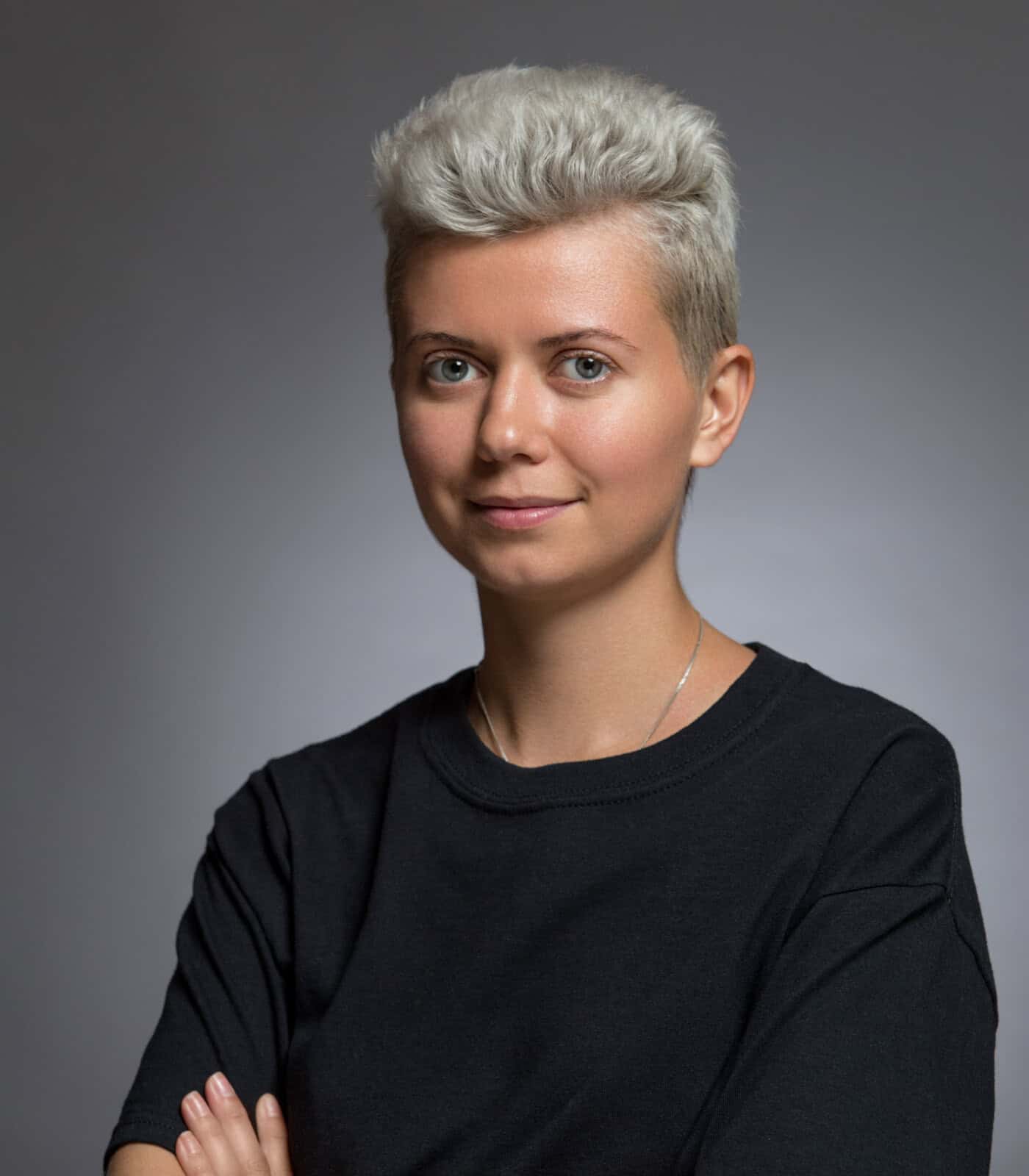 Modern woman with short platinum blonde hair in a black t-shirt, confident pose.